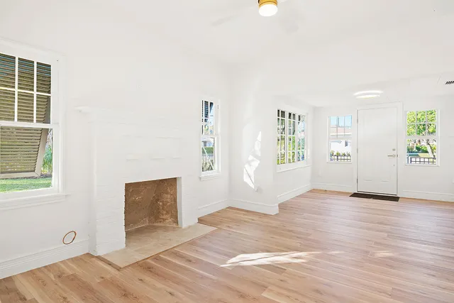 a view of an empty room with window and wooden floor