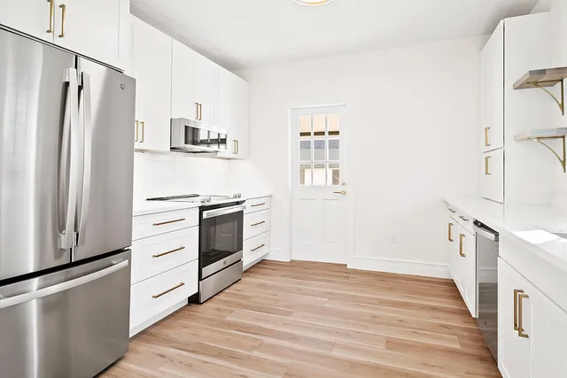 a kitchen with stainless steel appliances a refrigerator stove and white cabinets