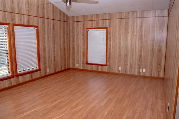 an empty room with wooden floor and windows