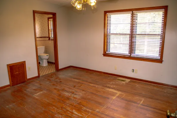 a view of an empty room with a window and wooden floor
