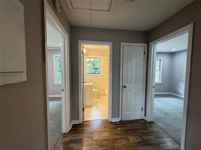 a view of a hallway with wooden floor and a bathroom