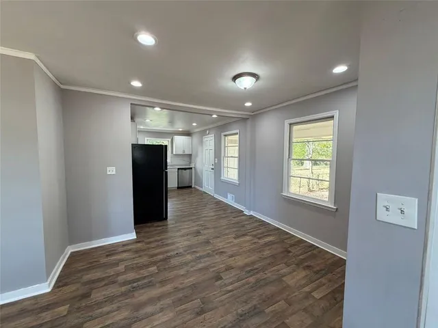 a view of an empty room with a window and a kitchen
