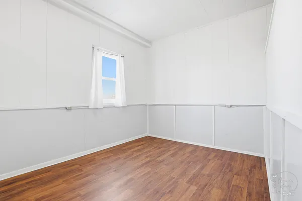 an empty room with wooden floor and cabinet