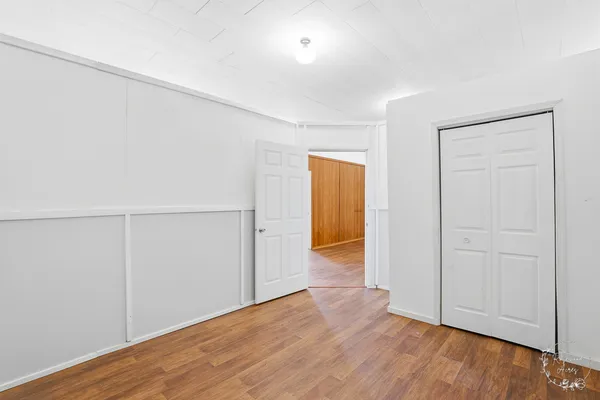 an empty room with wooden floor and closet area