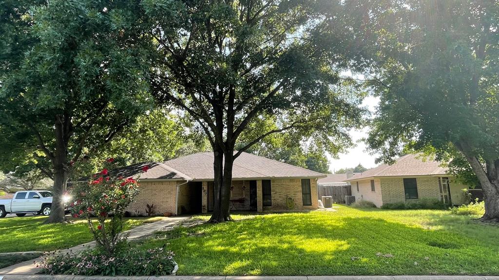 a front view of a house with a garden and trees