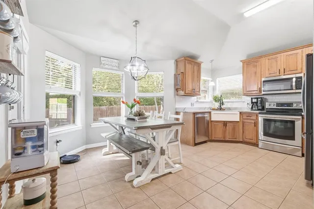 a kitchen with stainless steel appliances a table chairs and a large window