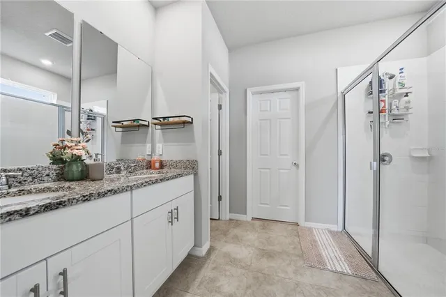 a bathroom with a double vanity sink a large mirror and shower