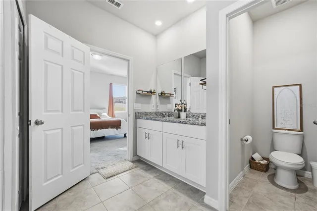 a bathroom with a granite countertop sink a toilet and a mirror