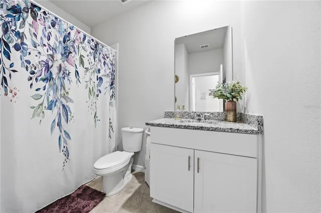 a bathroom with a granite countertop sink toilet and mirror