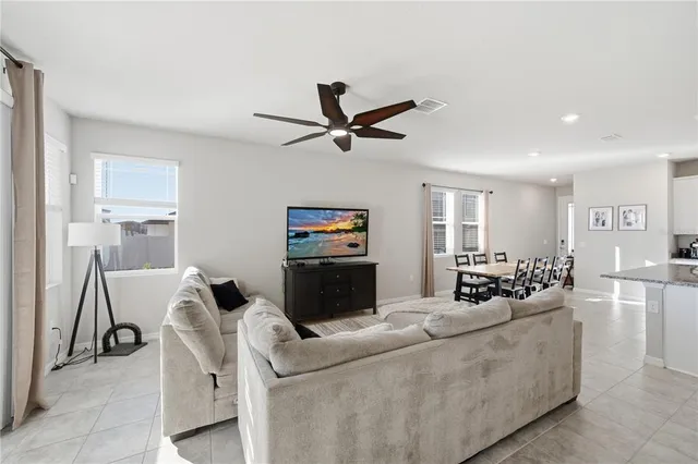 a living room with furniture a ceiling fan a lamp and a window