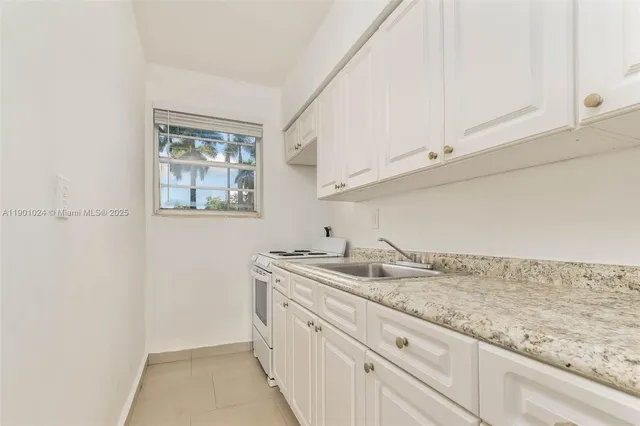 a kitchen with granite countertop white cabinets and a stove