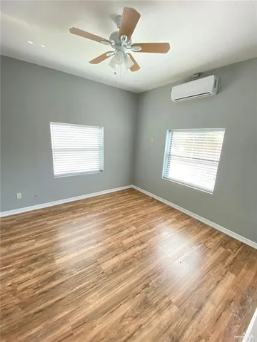 a view of an empty room with window and wooden floor