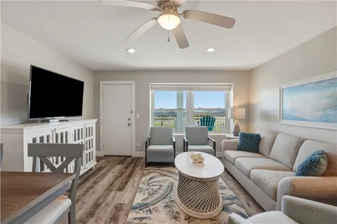 a living room with furniture a flat screen tv and kitchen view