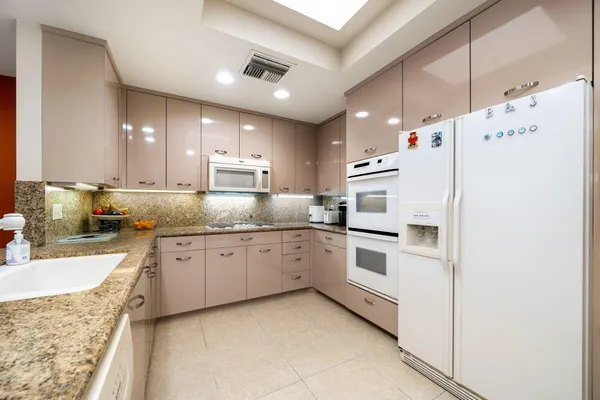 a kitchen with granite countertop white cabinets and white appliances