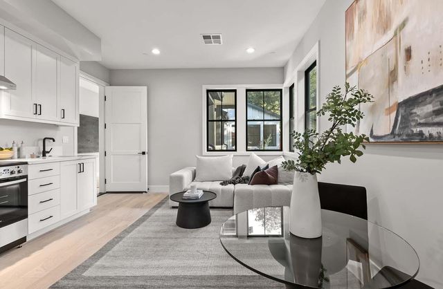 a living room with furniture a potted plant and kitchen view