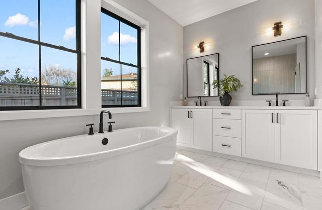 a bathroom with a double vanity sink and mirror with bathtub