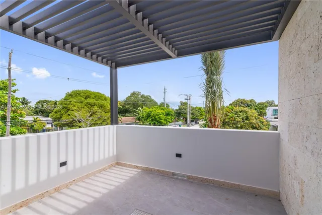 a room with lots of white furniture and a potted plant