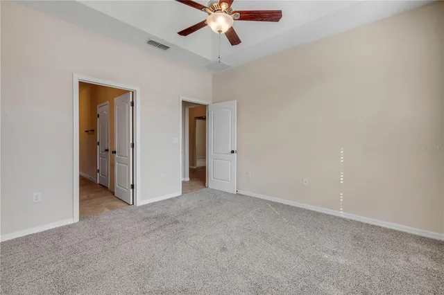 an empty room with closet and a ceiling fan