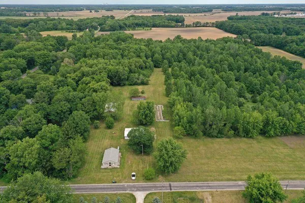 an aerial view of a residential houses with outdoor space and trees