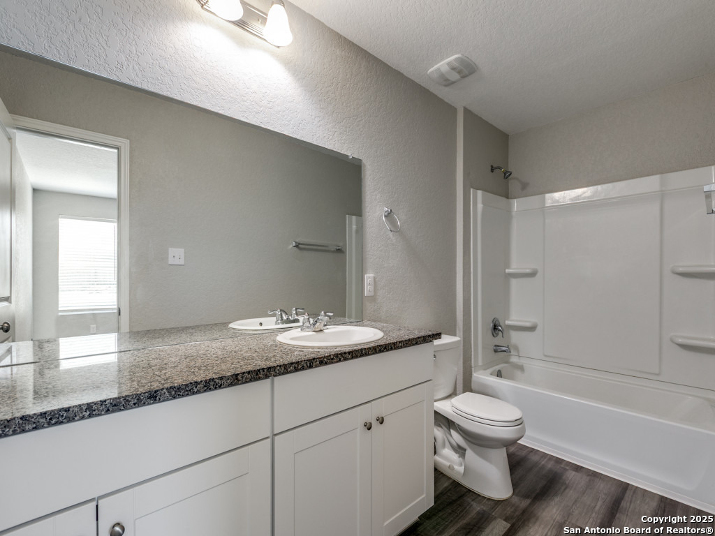 31593 Nimbus Drive Bulverde, TX 78163 - Photo 12 of 30 a bathroom with a granite countertop sink toilet and shower