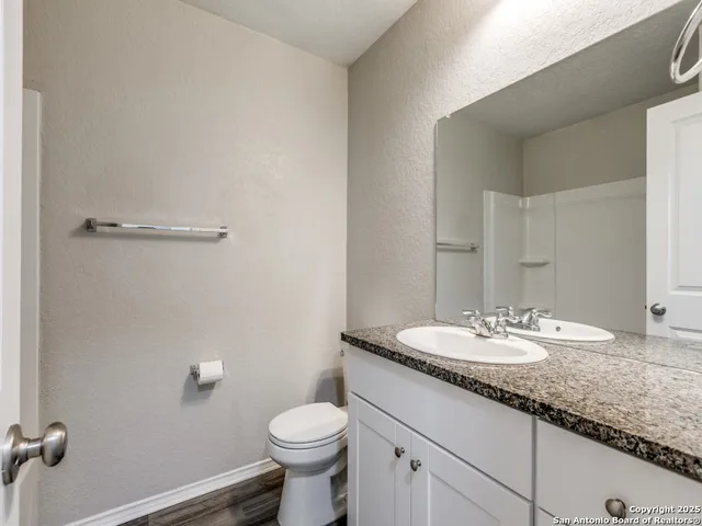 a bathroom with a granite countertop sink a toilet and a mirror