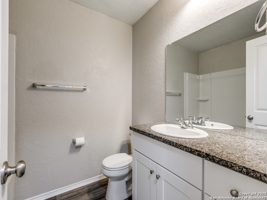 31593 Nimbus Drive Bulverde, TX 78163 - Photo 17 of 30 a bathroom with a granite countertop sink a toilet and a mirror