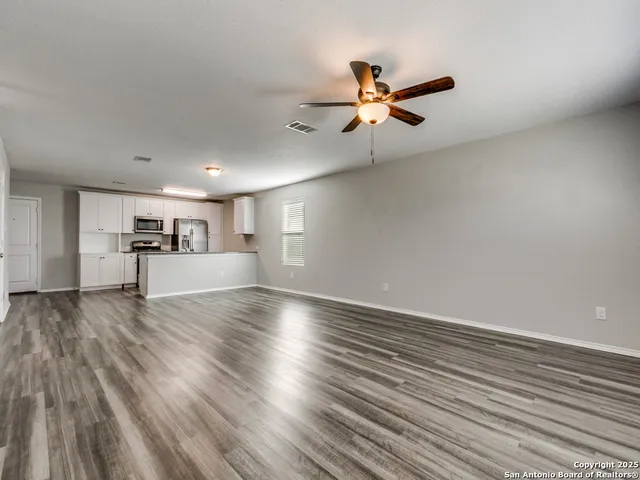 a view of empty room with wooden floor and fan