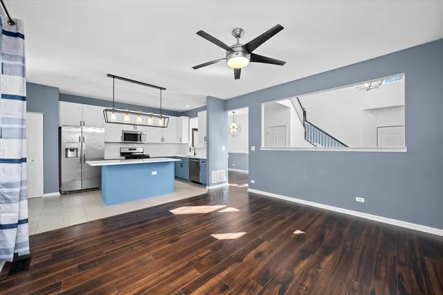 a kitchen with stainless steel appliances wooden floor and a refrigerator