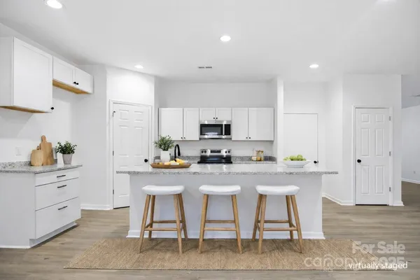 a large kitchen with stainless steel appliances granite countertop a stove a sink and white cabinets