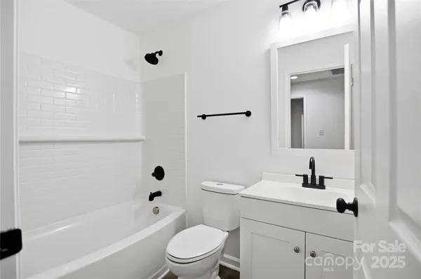 an empty room with a chandelier fan and windows