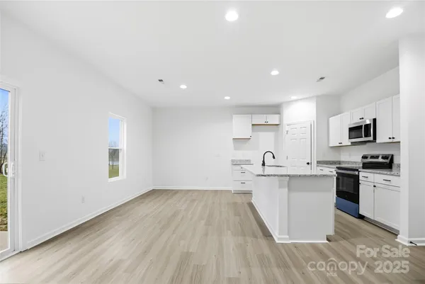 a kitchen with stainless steel appliances granite countertop a table chairs sink and cabinets