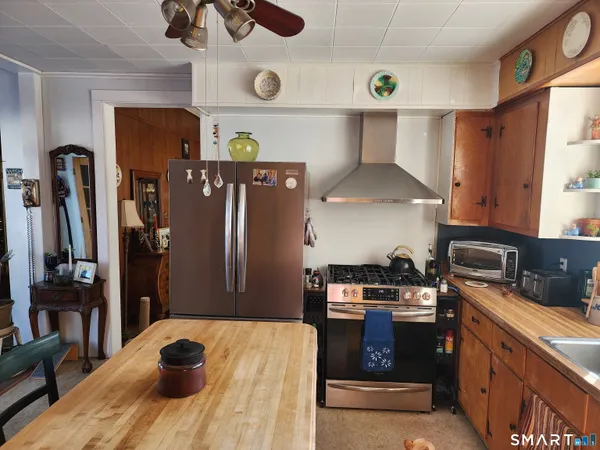 a kitchen with stainless steel appliances a sink a stove a refrigerator cabinets and dining table