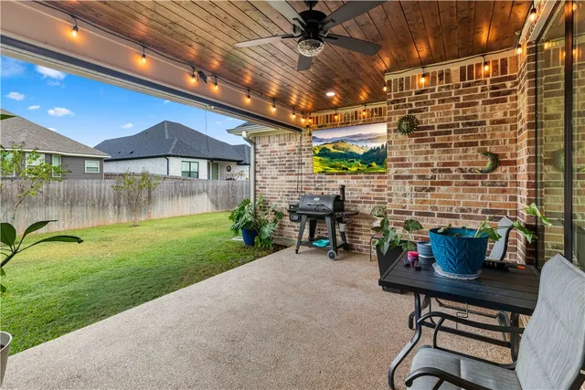 a patio with table and chairs and potted plants