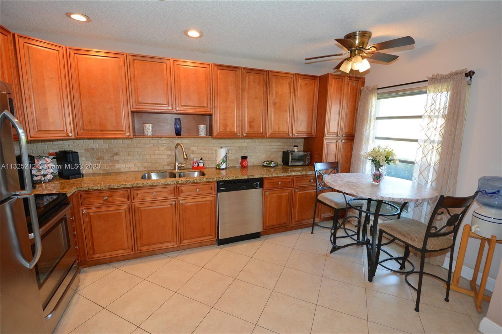 8936 Belle Aire Court, Unit 375 Boca Raton, FL 33433 - Photo 3 of 32 a kitchen with a sink dining table and chairs