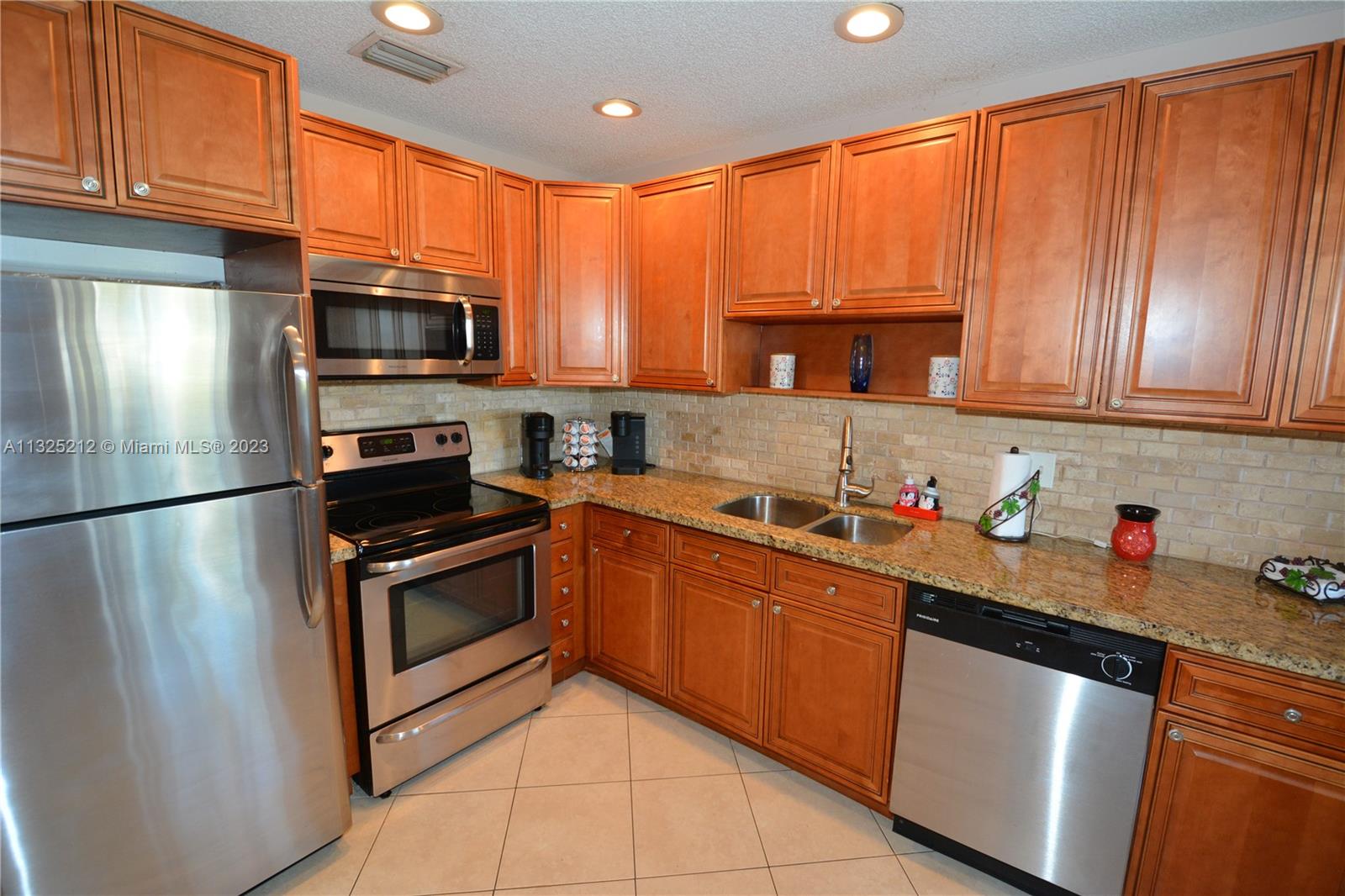 8936 Belle Aire Court, Unit 375 Boca Raton, FL 33433 - Photo 4 of 32 a kitchen with stainless steel appliances granite countertop a refrigerator stove a sink dishwasher and microwave with wooden cabinets