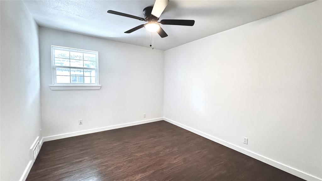 3315 Cedarcroft Lane Dallas, TX 75233 - Photo 13 of 19 an empty room with wooden floor ceiling fan and windows