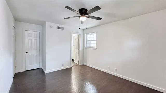 an empty room with wooden floor ceiling fan and windows