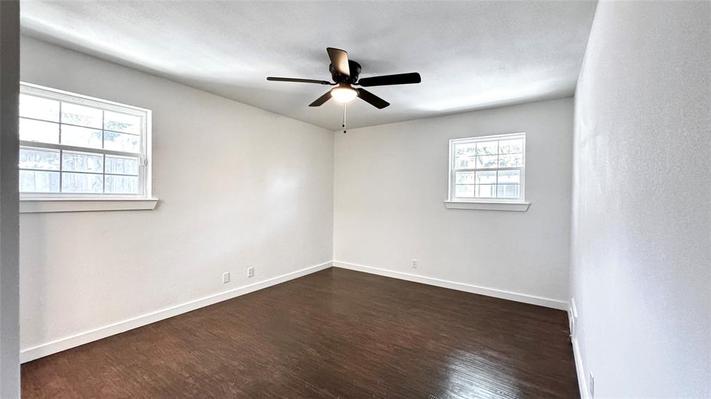 3315 Cedarcroft Lane Dallas, TX 75233 - Photo 17 of 19 an empty room with wooden floor ceiling fan and windows