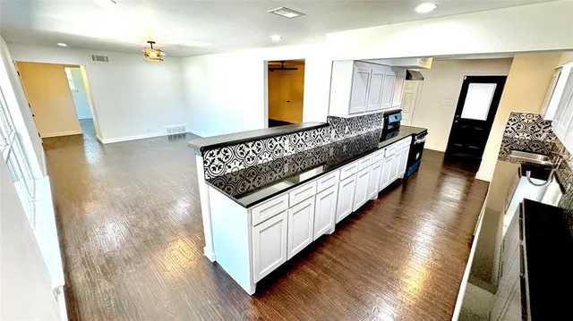 a kitchen with granite countertop a stove and a wooden floors