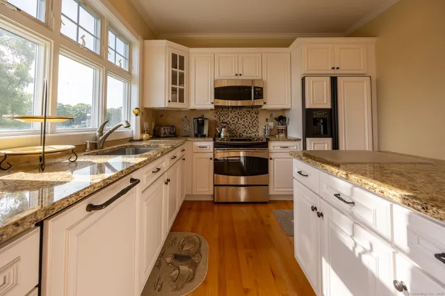 a large kitchen with stainless steel appliances granite countertop a stove a sink and a microwave