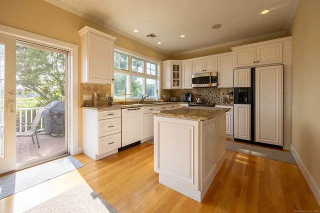 a kitchen with a sink a counter top space stainless steel appliances a large window and cabinets