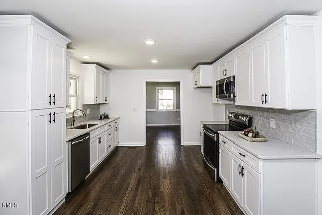 a kitchen with stainless steel appliances white cabinets a sink a stove a refrigerator and white cabinets