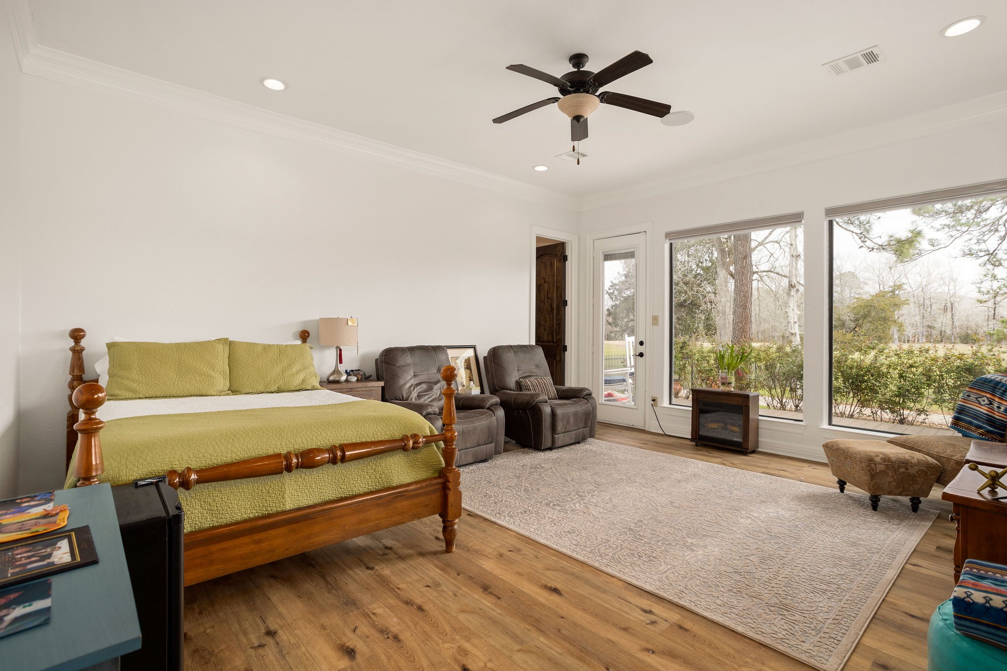 10210 Stidham Road Conroe, TX 77302 - Photo 22 of 39 a spacious bedroom with a bed a couch and a large window with wooden floor