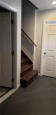 a view of an empty room with wooden floor and stairs