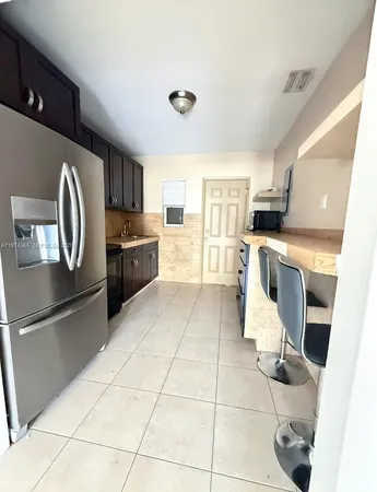a kitchen with granite countertop a refrigerator and a stove top oven