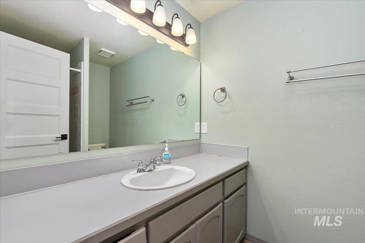 9215 West Preece Street Boise, ID 83704 - Photo 14 of 22 Bathroom vanity featuring a single basin sink, a gray countertop, and lower cabinetry with gray finishes