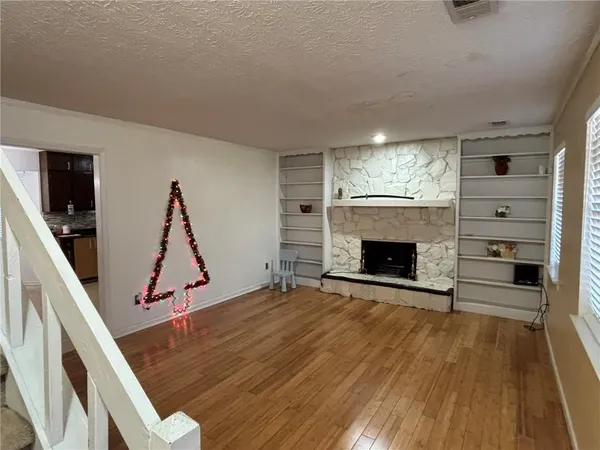 a view of an empty room with wooden floor fireplace and a window