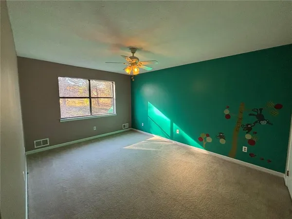 an empty room with windows and ceiling fan