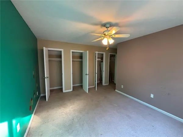 an empty room with closet and a ceiling fan