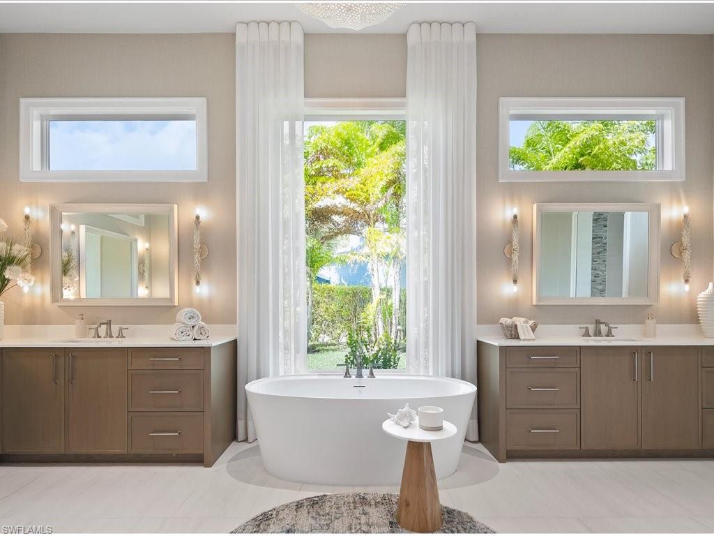 6730 Sable Ridge Lane Naples, FL 34109 - Photo 17 of 50 a bathroom with a double vanity sink a large mirror and a bathtub